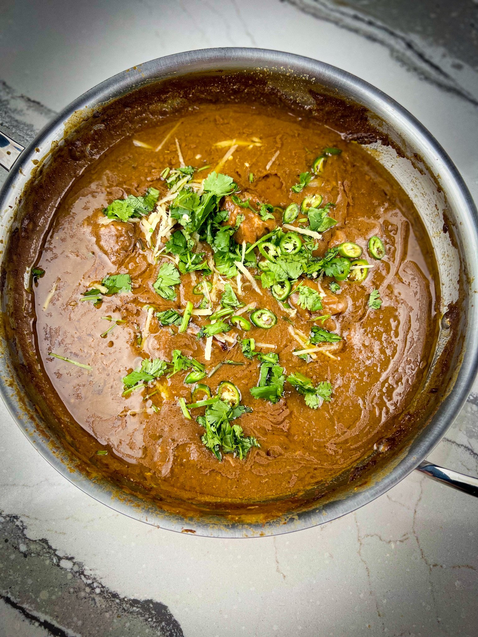 nihari with garnish in a pot.